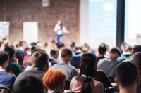 Erwachsene Menschen bei einer Konferenz hören einer Sprecherin zu, die im großen Konferenzsaal einen Vortrag hält. Geschäfts- und Unternehmerkonzept.
