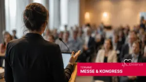 Referentin bei einer jemah Messe & Kongress Veranstaltung spricht vor Publikum an einem Pult mit Mikrofon.