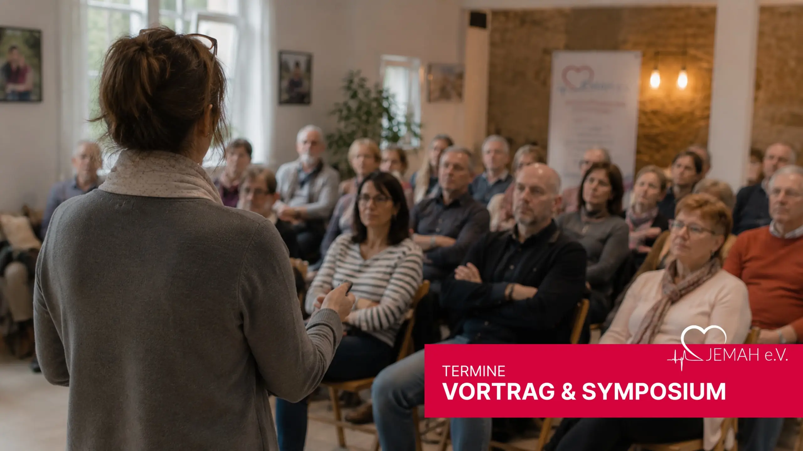 Referentin bei einer jemah Messe & Kongress Veranstaltung spricht vor Publikum an einem Pult mit Mikrofon.